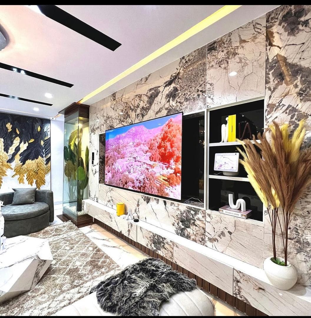 A finished, marble-clad living room with a large wall-mounted screen, the property once it was transformed