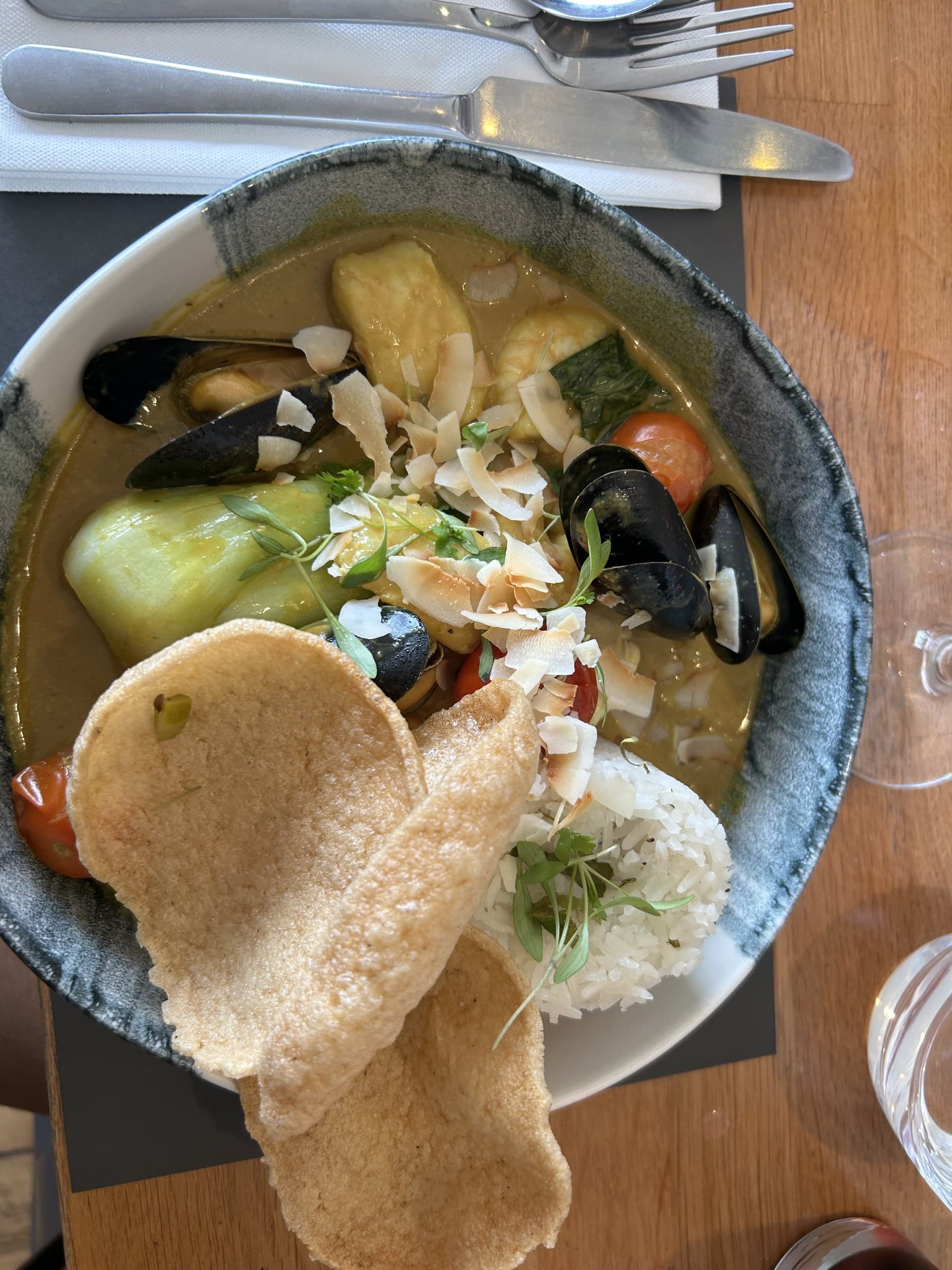 A Cornish seafood curry with mussels, poppadoms and rice, seen from above