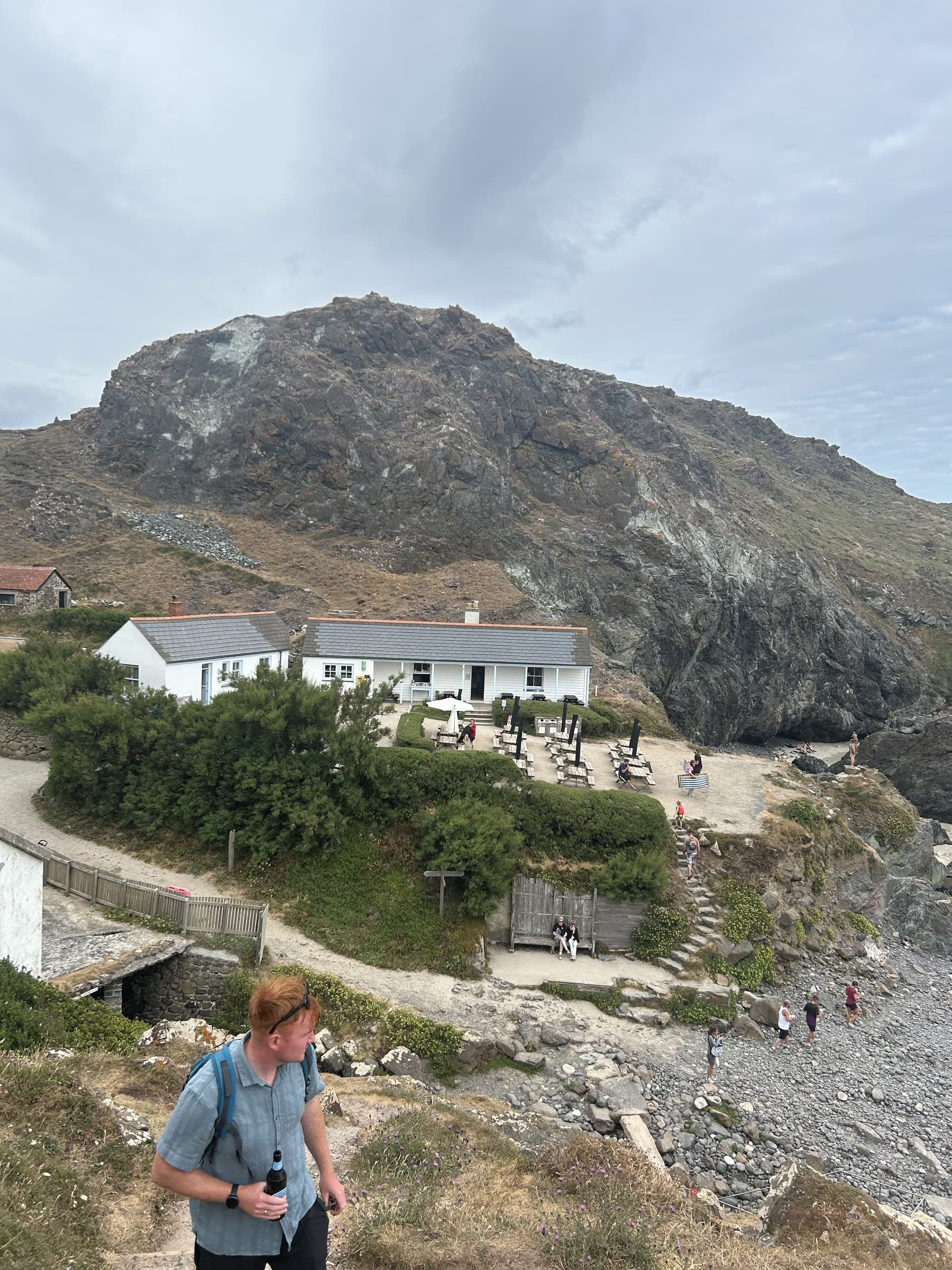 Jasmine's partner on the cliff path above Kynance Cove, the beach café and cove below